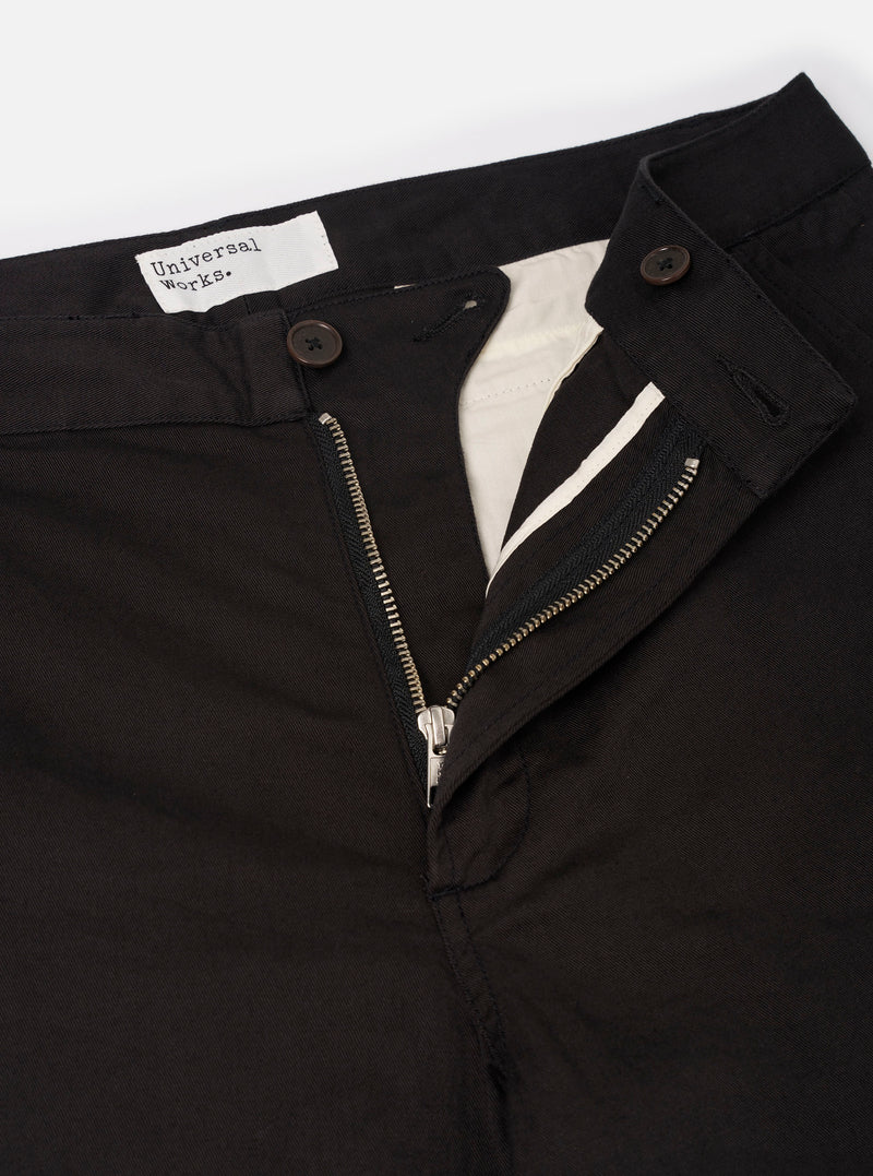 Close-up detail shot of the Black Twill Aston Pant on a neutral studio background. Focuses on the pointed button-flap back pocket design, fine 3/1 cotton twill weave texture, and tight seam construction.