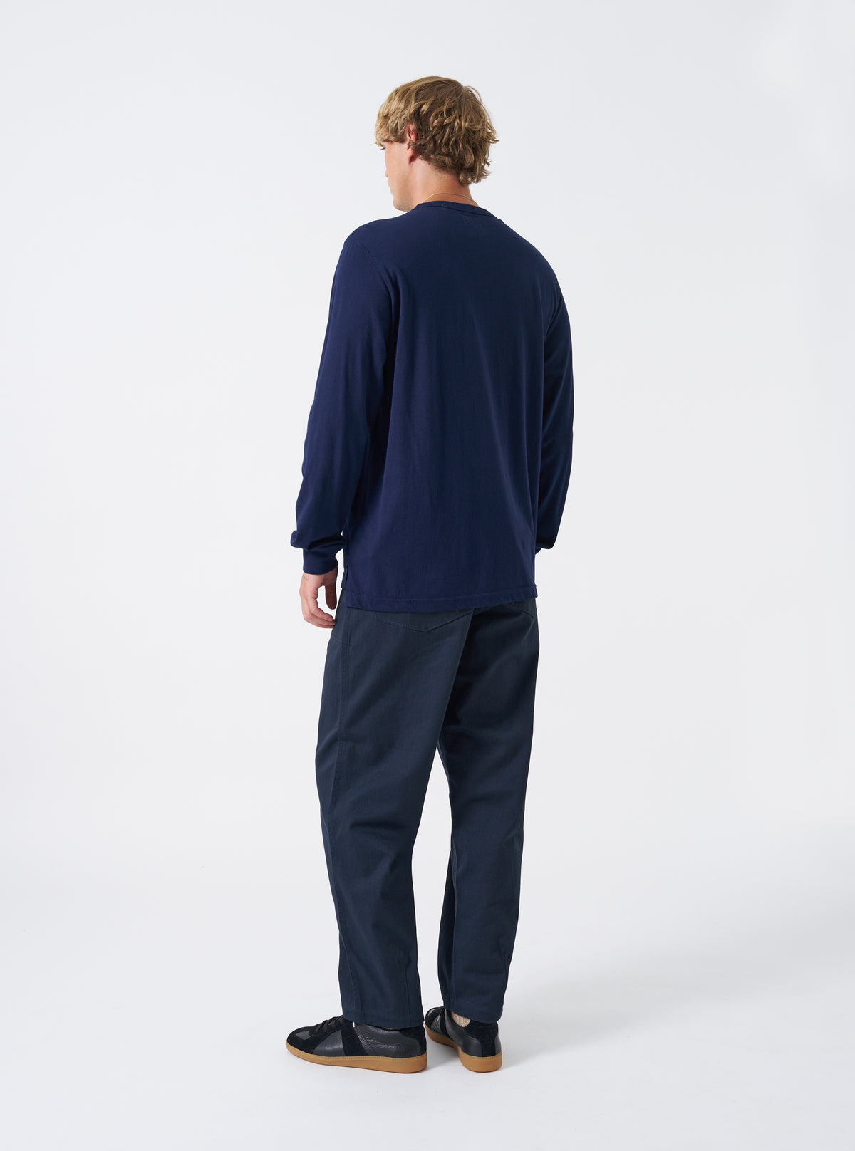 Side profile view of a model wearing the Navy Twill Fatigue Pant against a neutral background. Highlights the straight leg line, side seam construction, and structured fit around the hips and legs.