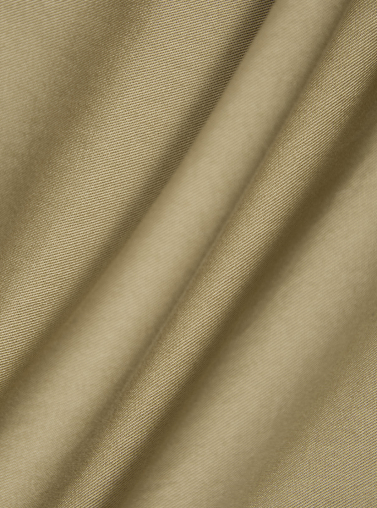 Close-up of the sand twill double pleat pant fabric. The material is draped to show texture. The background is a plain white surface.