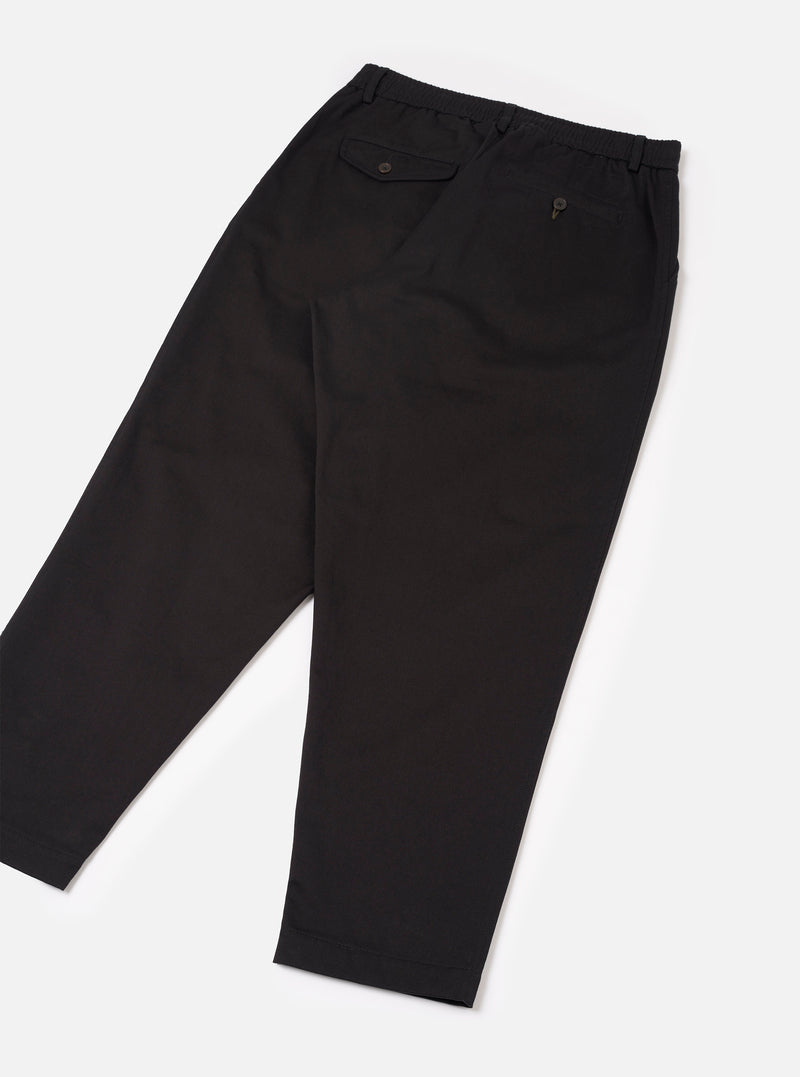 Rear view of the Black Twill Pleated Track Pant presented on a plain white backdrop. Showcases the back welt pocket design, elasticated waistband with drawstring, and clean tapered leg seam lines.