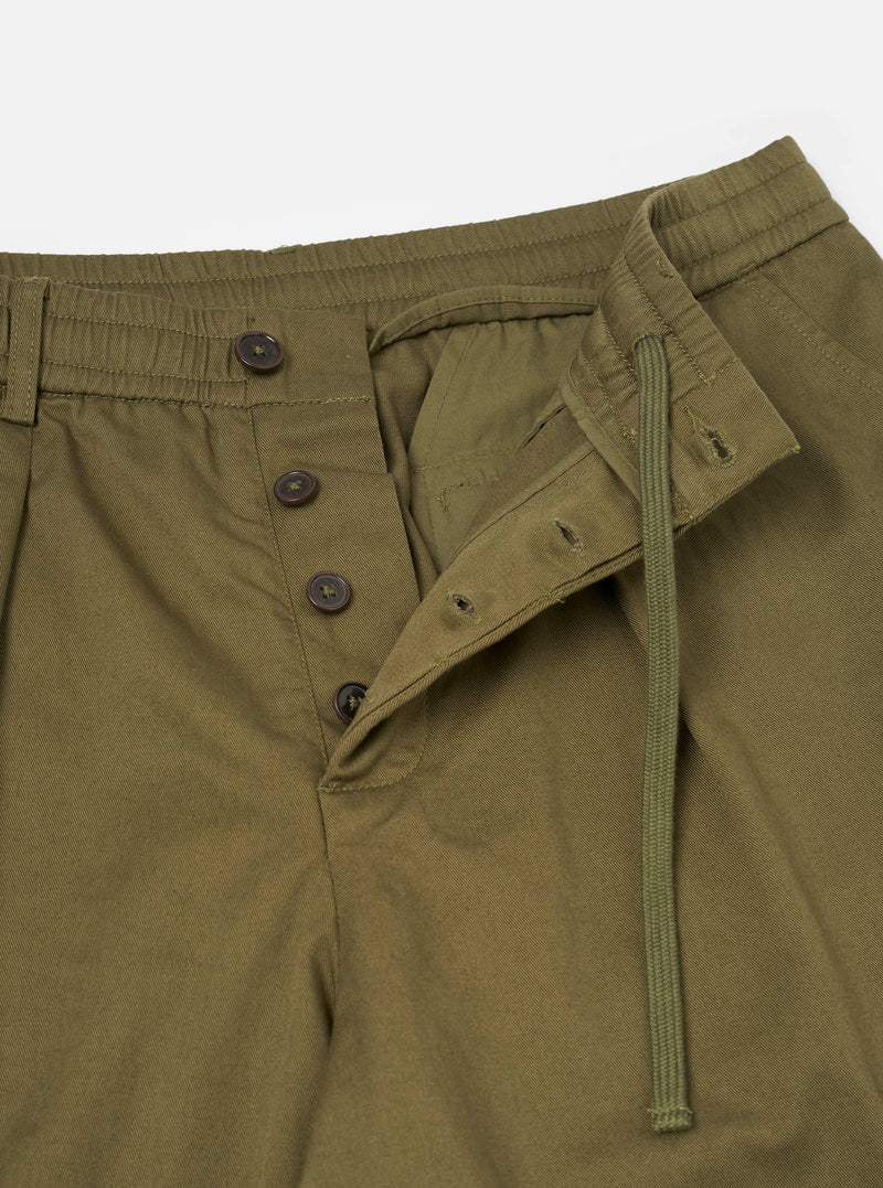 A close-up image of the Light Olive Twill Pleated Track Pant on a white background. Focuses on the fine light olive twill texture, drawstring cord details, front pleat, and waist construction.