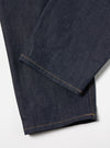 Close-up of Indigo 13oz Selvedge Denim Military Chino on a white surface. The dark indigo denim shows subtle texture and tan stitching detail.