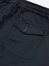 The Navy Twill Beach Short is displayed from the back as a flat lay against a plain white background. The image highlights the elasticated waistband and a single rear patch pocket featuring two metal eyelets near the bottom. The navy blue cotton twill fabric shows a distinct diagonal weave.