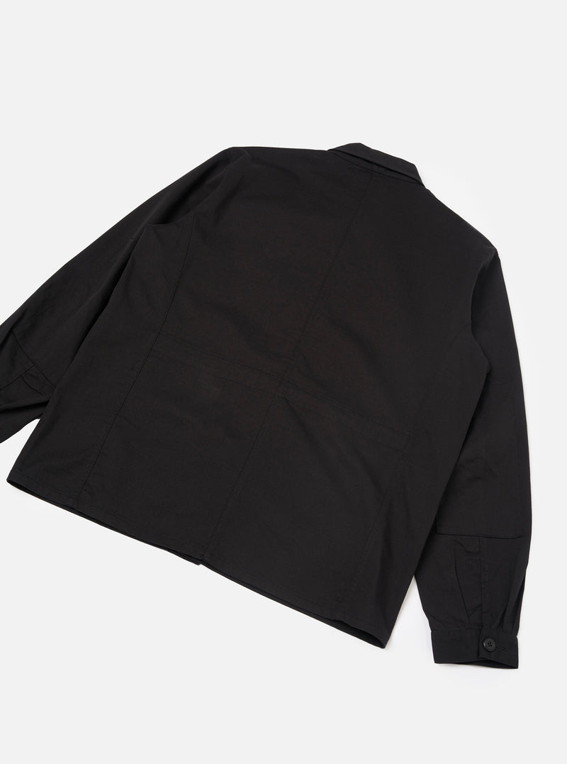 Back view of the Black Twill MW Fatigue Jacket displayed against a plain white background. The shot highlights the clean back panel construction, straight hem, structured cotton twill fabric, and long sleeve cuffs.