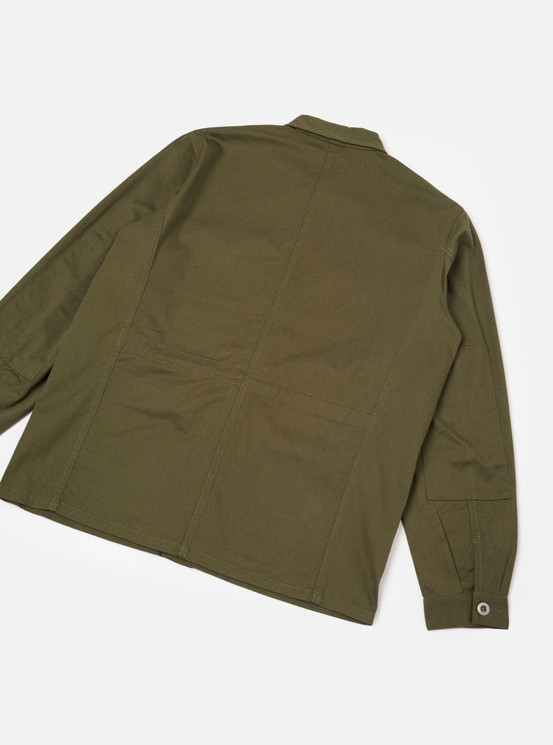 Back view of the Light Olive Twill MW Fatigue Jacket set against a plain off-white background. The shot shows the clean back yoke, structured shoulder seams, straight hemline, and durable light olive cotton twill weave.