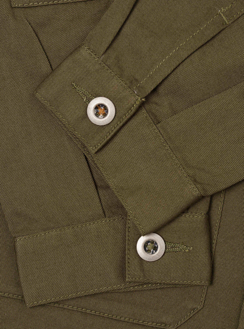 Detailed close-up shot of the Light Olive Twill MW Fatigue Jacket on a plain white background. The focus is on the concealed front button closure, internal waist drawcord, and precise seam construction.