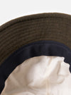 Close-up of the inside of a cableami® Olive Recycled Wool Army Hat, showing the olive wool exterior, navy trim, and cream-colored lining against a white background.