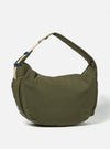 The master-piece x Universal Works Olive Large Canvas Shoulder Bag is shown from the back as a flat lay against a plain white background. The image highlights the webbing strap designed for a suitcase handle, two outer side pockets, and the tonal texture of the olive green recycled fabric.