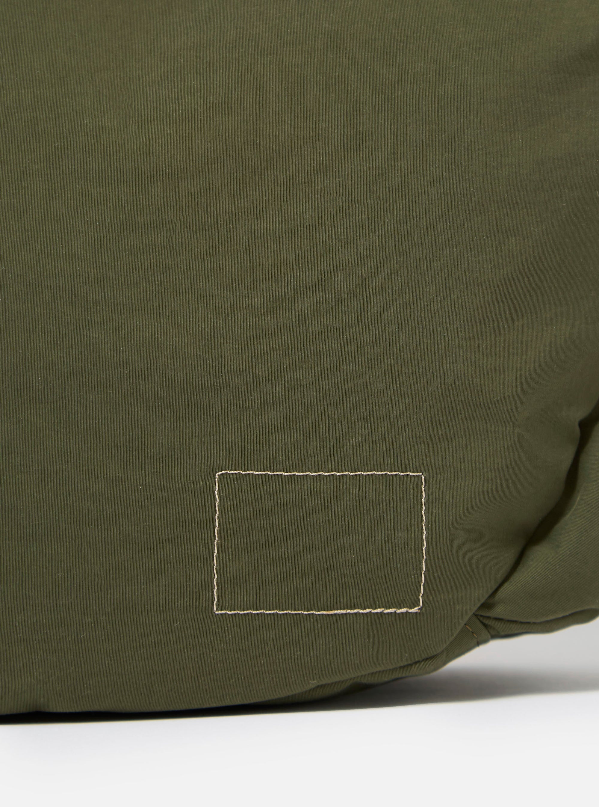 The master-piece x Universal Works Olive Medium Canvas Shoulder Bag is shown from the back as a flat lay against a plain white background. The image highlights the horizontal webbing strap designed for a suitcase handle and the adjustable, detachable shoulder strap. The bag is made from olive green canvas and features a clean, rectangular silhouette.