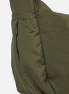 The master-piece x Universal Works Olive Medium Canvas Shoulder Bag is shown from the back as a flat lay against a white background. The image highlights the adjustable olive webbing strap, the rear compartment, and the smooth canvas fabric.