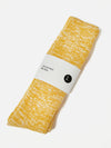 The Yellow Slub Knit Sock on a white surface. The sock is folded and wrapped with a Universal Works label. The sock has a textured, slub knit pattern.