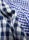 Close-up of the Blue Gingham Mix Pyjama Short fabric. Features a blue and white checkered pattern. The material is softly folded on a plain surface.