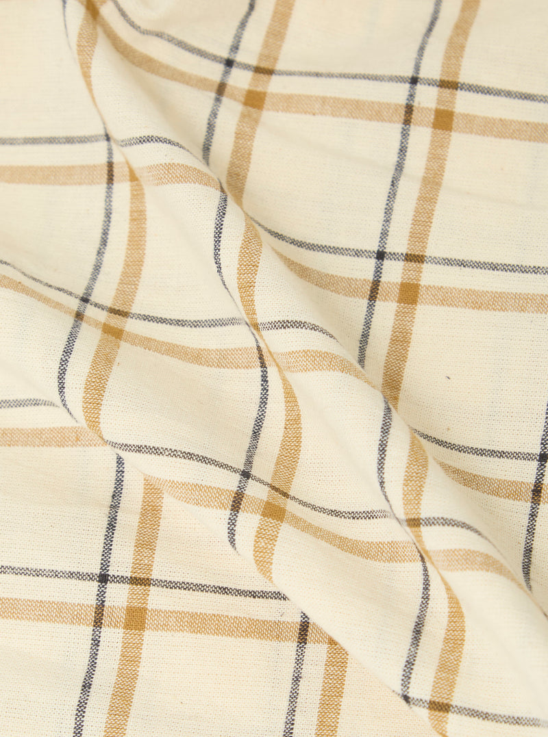 Close-up of the Multi PJ Plaid 3 Pack Boxer Short fabric. The material is a light cream color with gold and navy plaid lines. The fabric is folded on a white surface.