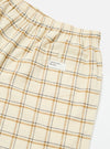 Close-up of the Ecru PJ Plaid Boxer Short on a white surface. The plaid pattern features ecru, tan, and navy lines. Elastic waistband and a back pocket with a button are visible.