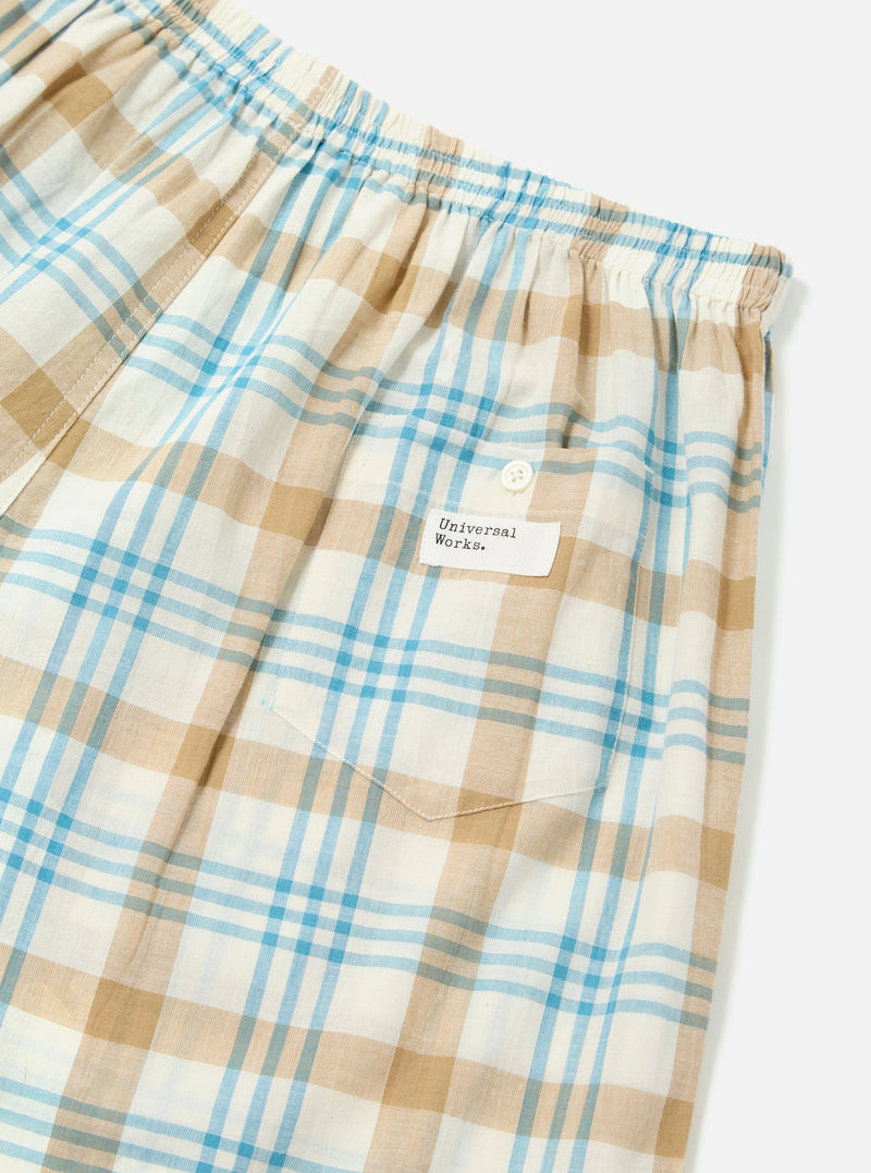 Close-up of the Ecru Madras Check Boxer Short on a white background. The fabric is a light plaid with ecru, tan, and blue lines. Features an elastic waistband and a small pocket.