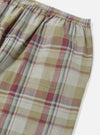 Close-up of the Green Kip Check Long Pyjama Set bottoms. The plaid pattern features beige, red, and blue on a white background. Elastic waist and side pocket detail. On a white surface.