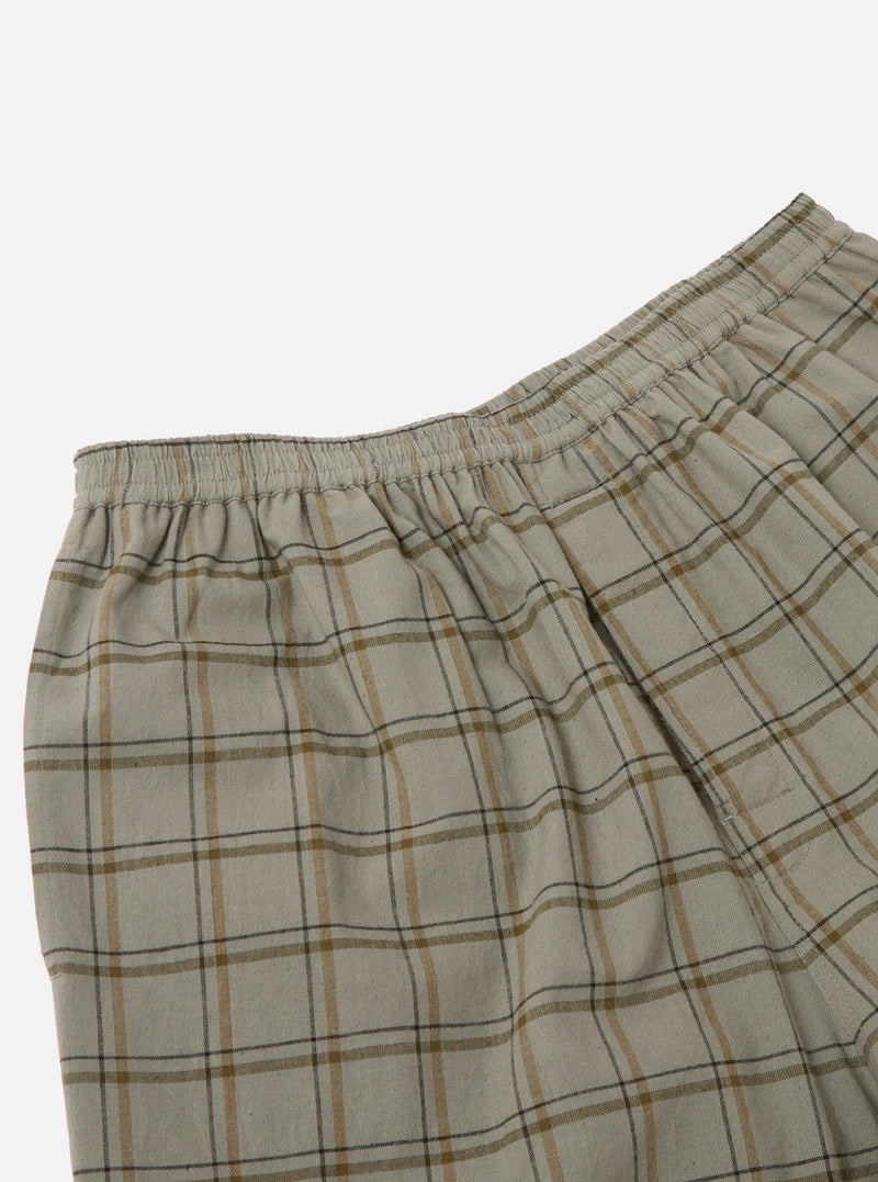 Close-up of the Green PJ Plaid Pyjama Short. The shorts feature a green and brown plaid pattern and an elastic waistband. Shot against a white background.