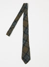 The Brown/Charcoal Ikat Twill Check Tie is displayed on a white surface. The tie features a brown and charcoal plaid pattern with hints of blue and red.