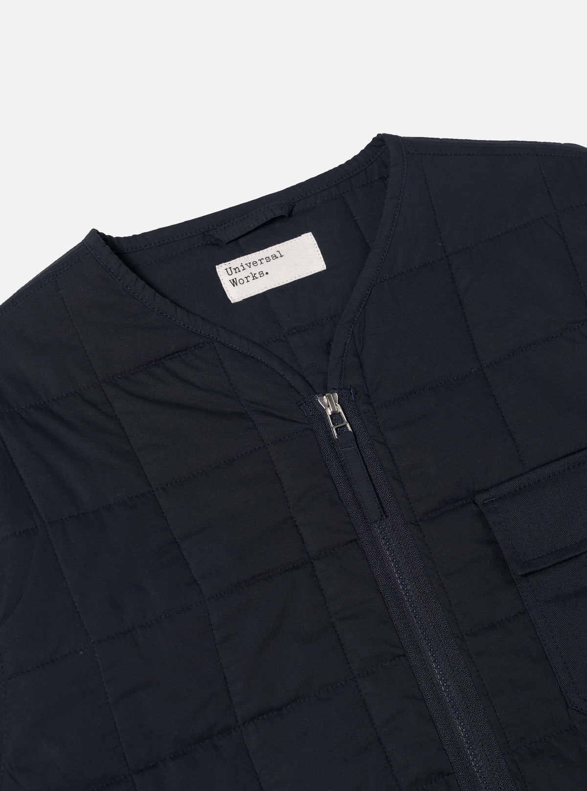 Close-up of the Navy Quilt Cotton Military Liner Jacket on a white background. The quilted jacket features a zip front and small pocket detail.