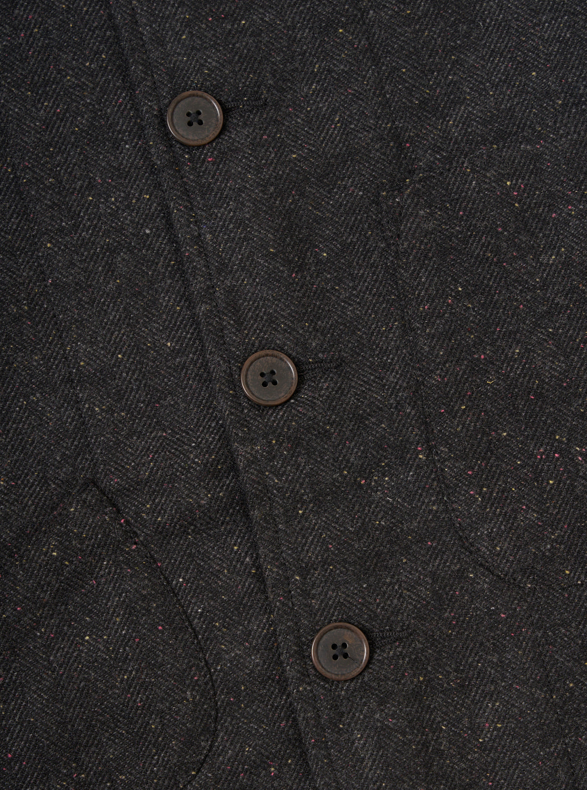 Close-up of the Black Salt N Pepper Tweed Station Jacket showing the tweed texture and button details. The jacket is displayed on a flat surface.