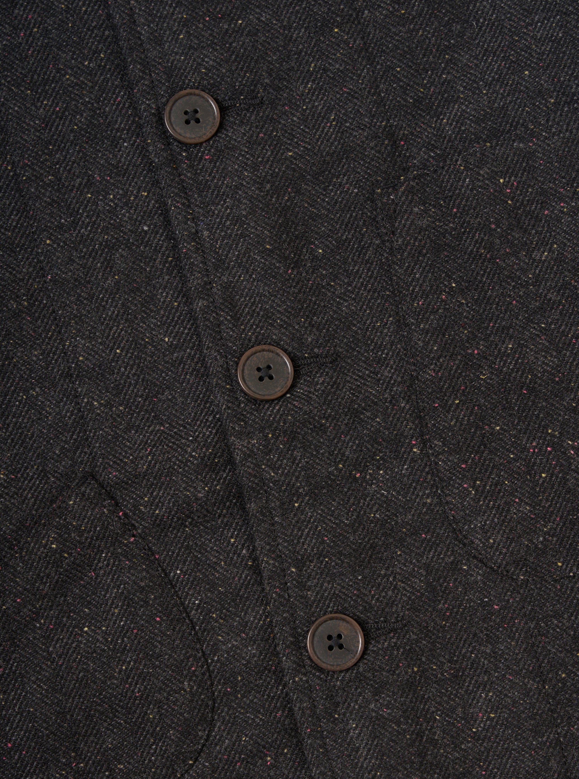 Close-up of the Black Salt N Pepper Tweed Station Jacket showing the tweed texture and button details. The jacket is displayed on a flat surface.