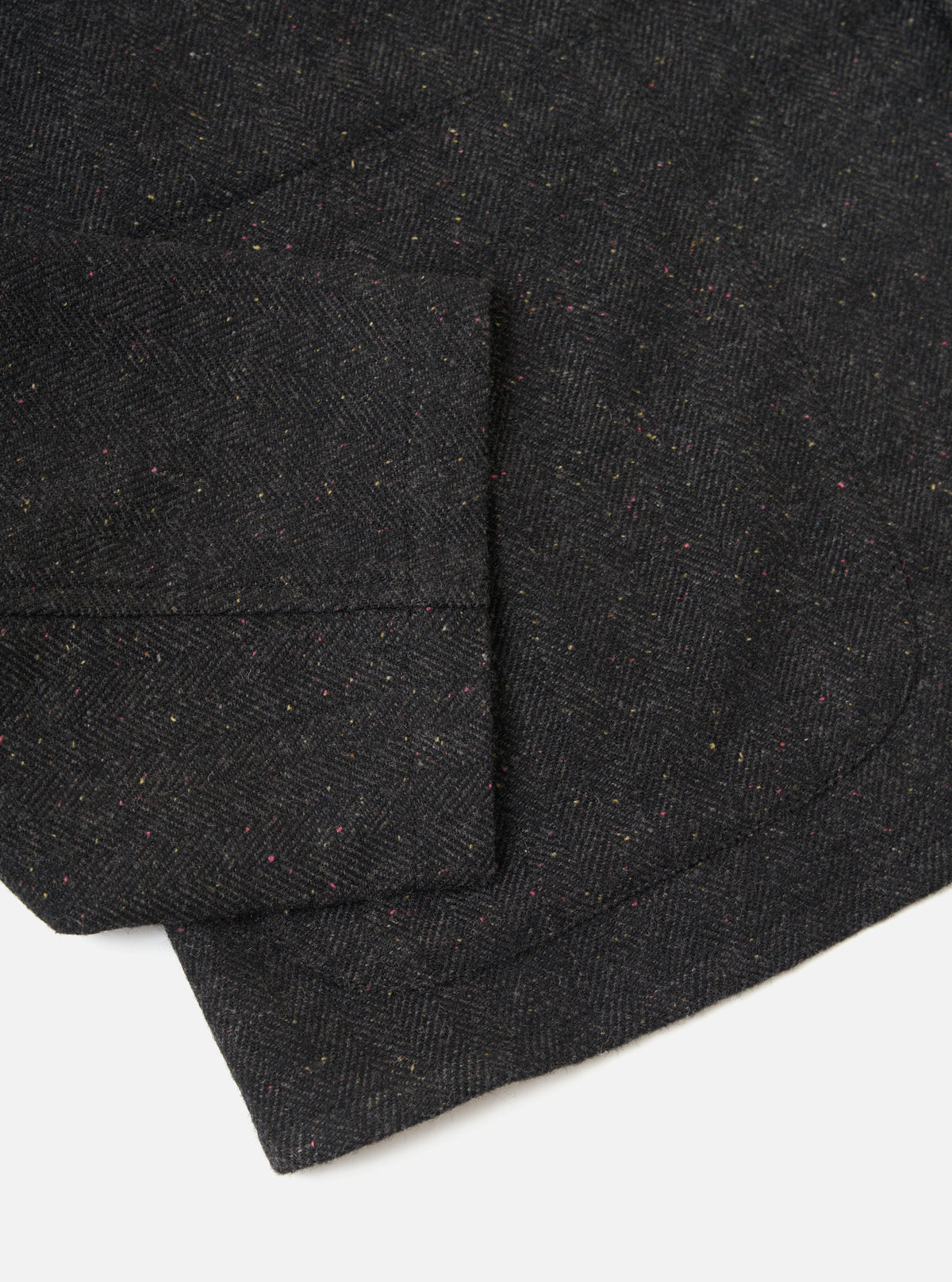 Close-up of the Black Salt N Pepper Tweed Station Jacket. The jacket is displayed on a white background, showing the texture and detail of the tweed fabric.