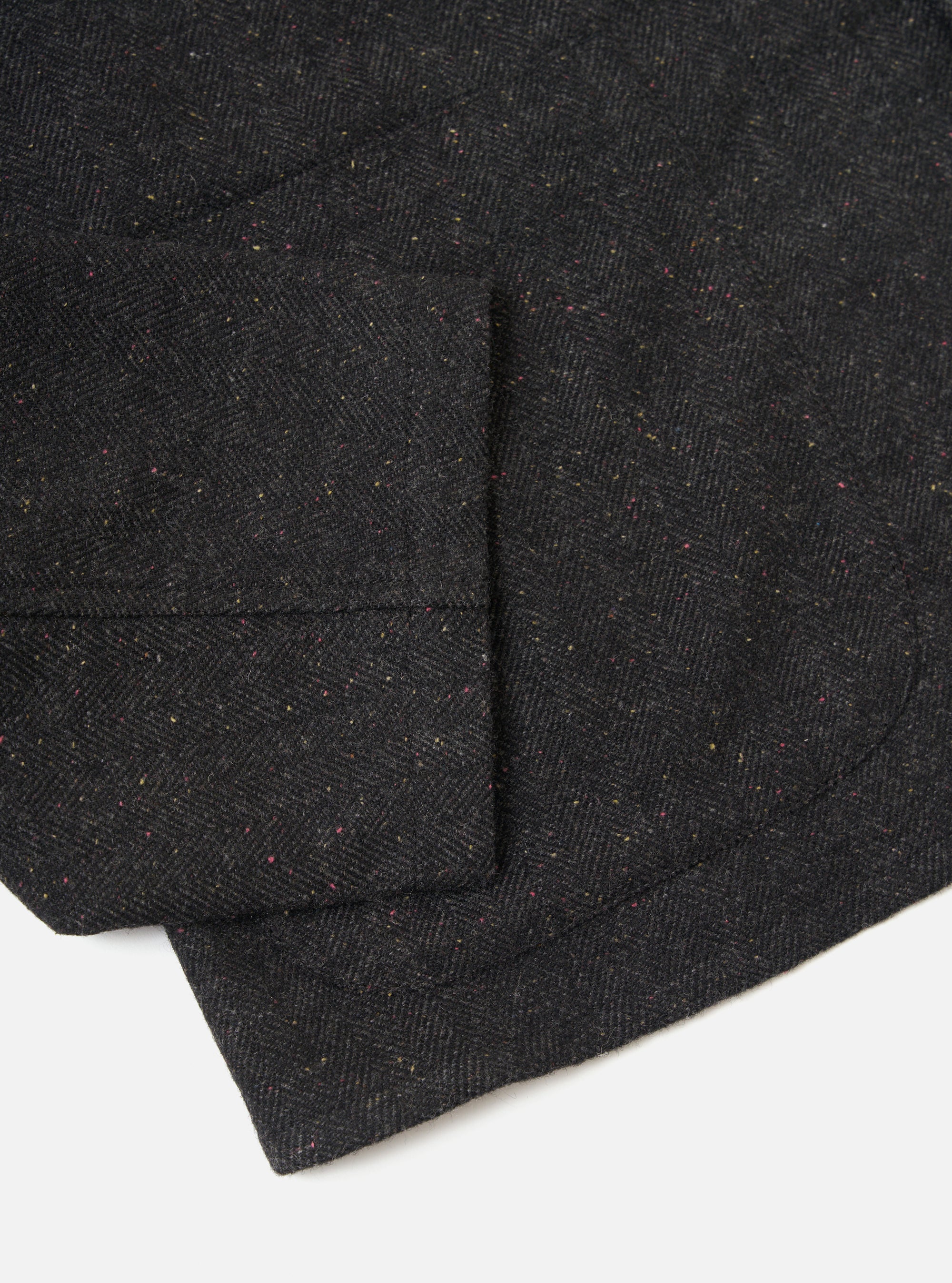 Close-up of the Black Salt N Pepper Tweed Station Jacket. The jacket is displayed on a white background, showing the texture and detail of the tweed fabric.
