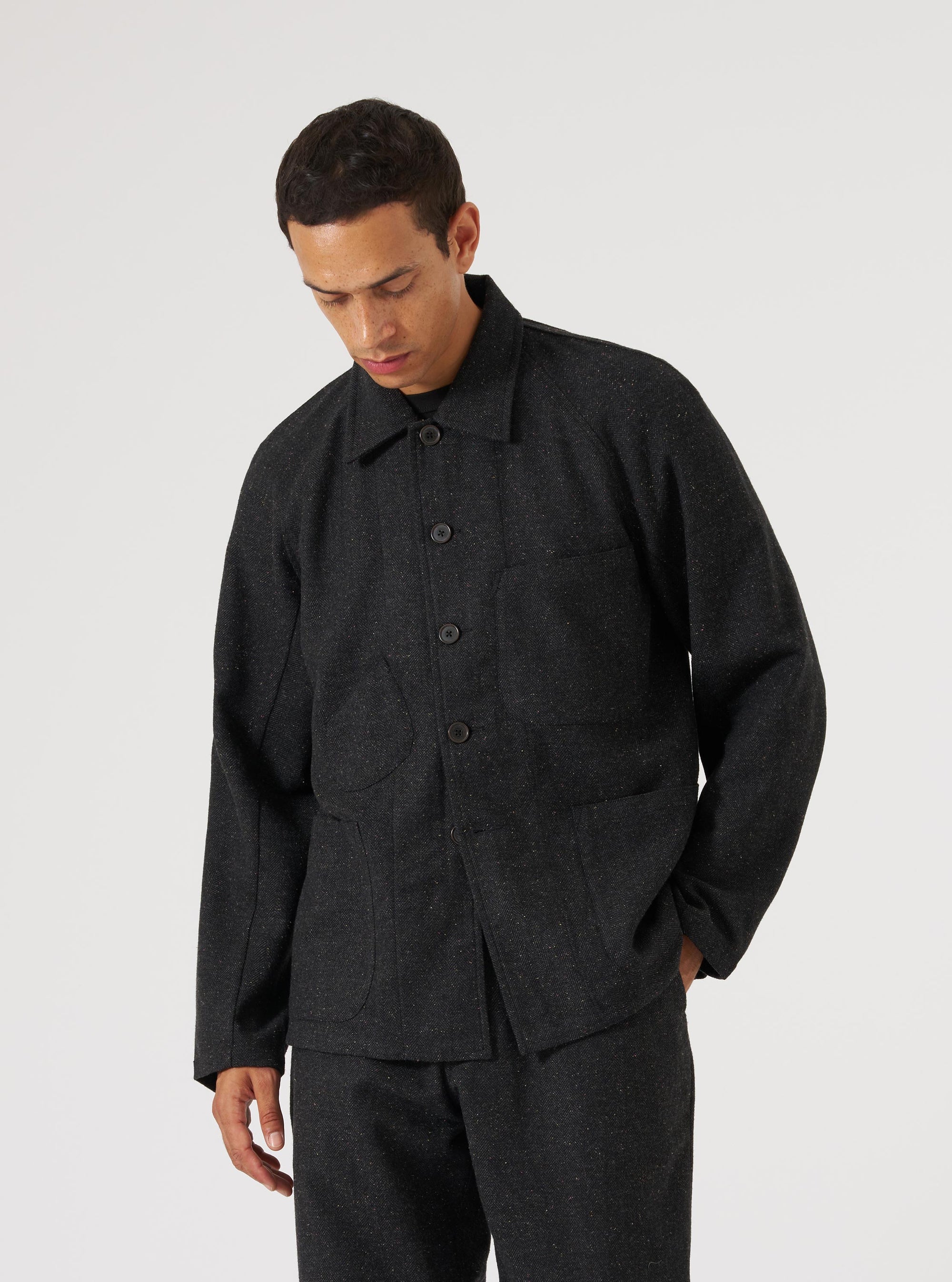 A model on a white background wears the Black Salt N Pepper Tweed Station Jacket. The jacket is a dark tweed with a button-up front and patch pockets.