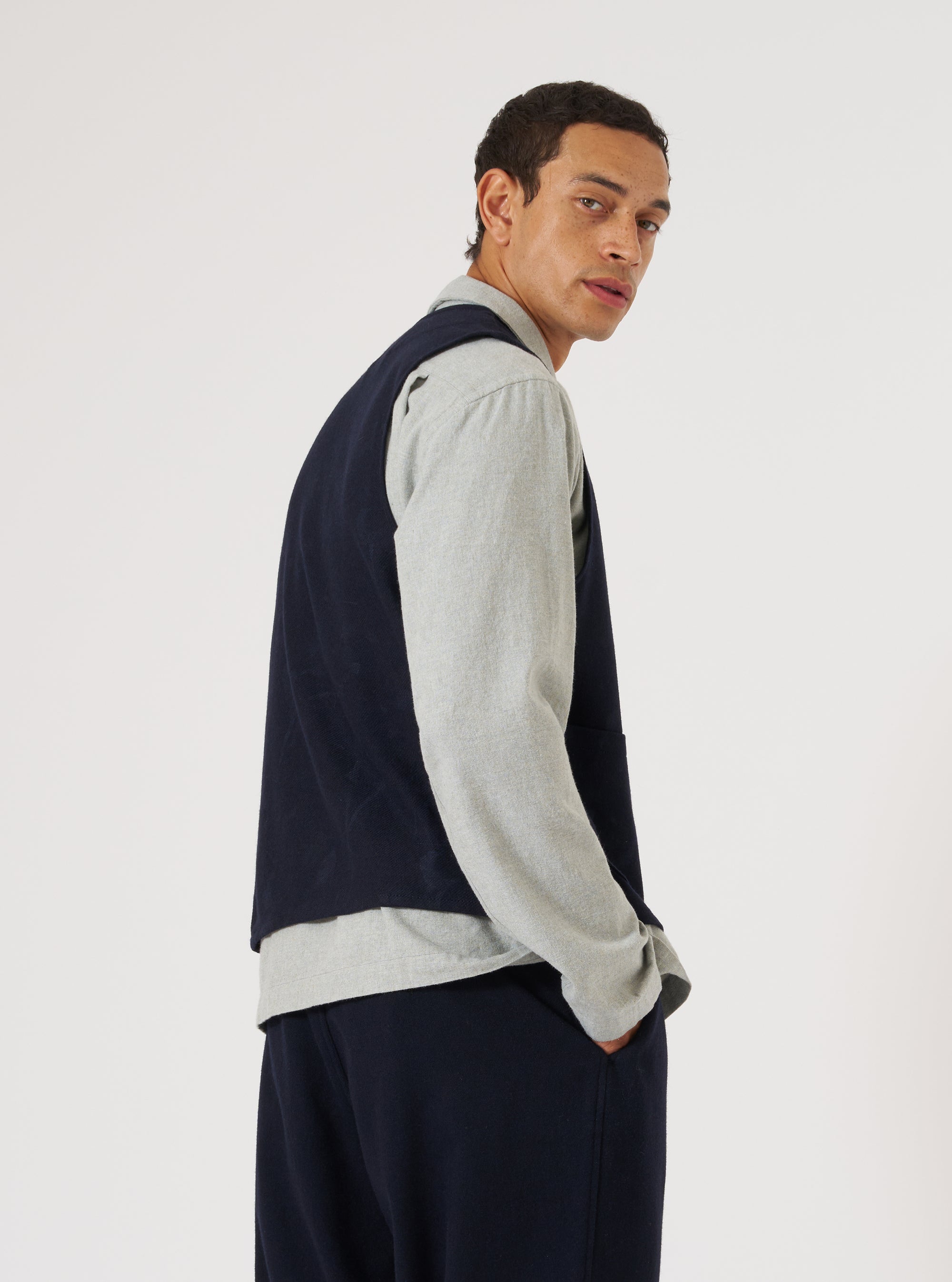 A model in a Navy Flower Print Flannel Operators Gilet, layered over a grey shirt. The gilet is dark blue. Shot in a white studio.