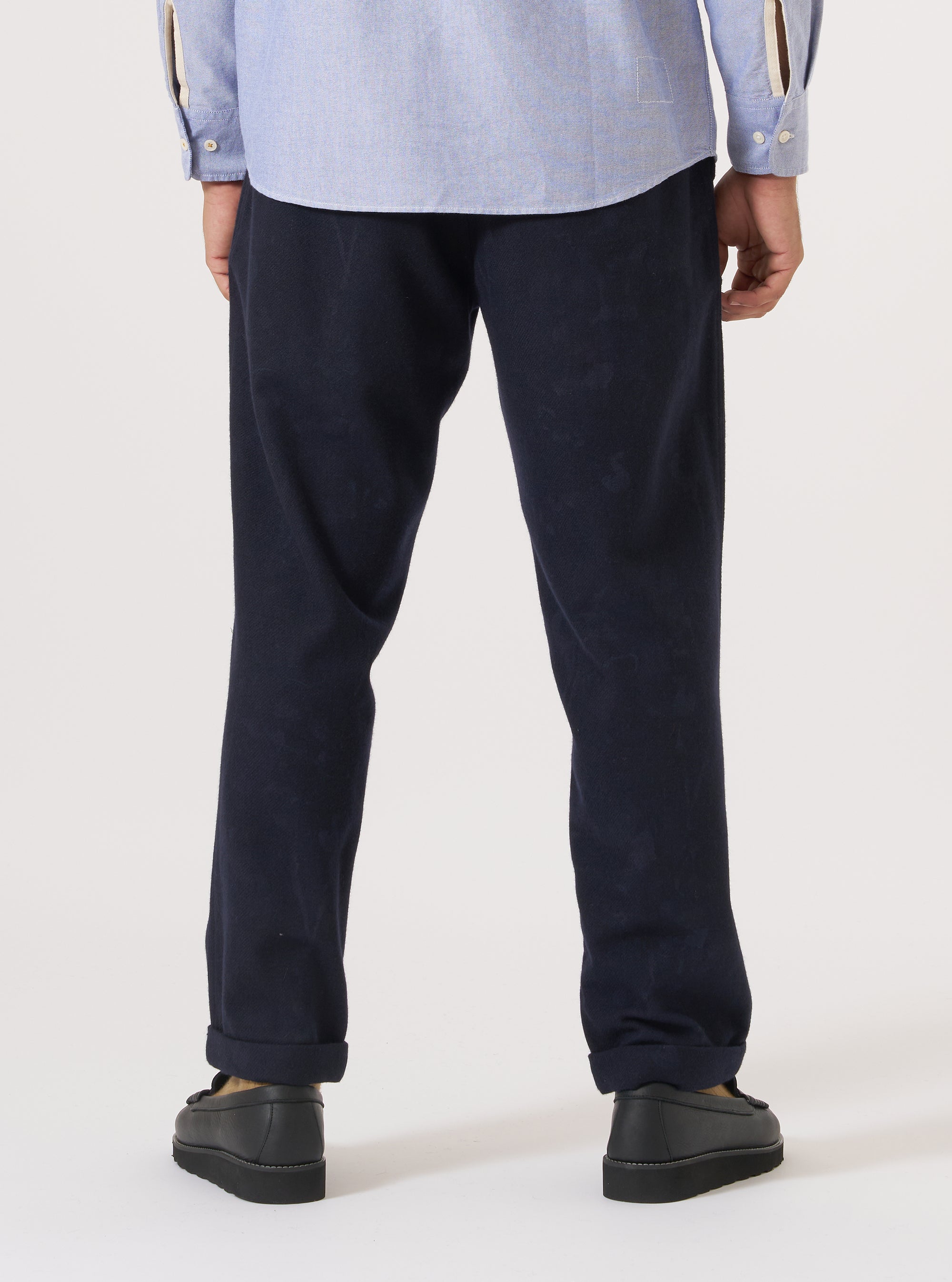 Back view of a model wearing the Navy Flower Print Flannel Super Chino, paired with a light blue shirt and black shoes, against a white backdrop.