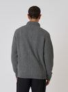 Back view of a model wearing a grey textured merino knit Charlie Cardigan. The cardigan has a waffle knit texture. Studio shot on a white background.