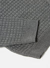 Close-up of the grey textured Merino knit Charlie Cardigan on a white surface, showcasing the intricate knit pattern and soft texture of the cardigan.