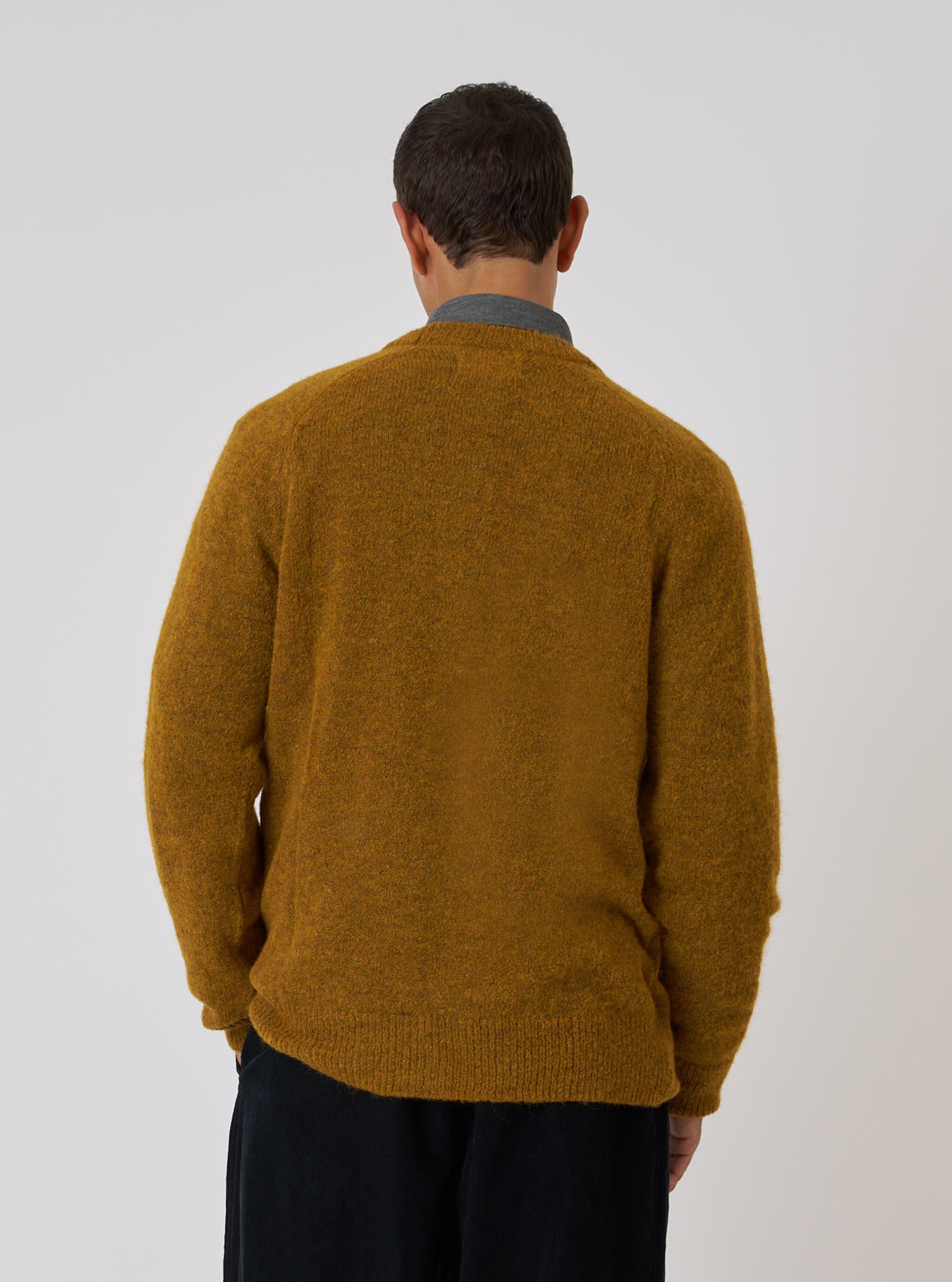 Back view of a model wearing a Gold Alpaca Knit Lyon Crew sweater. The sweater is gold and made of alpaca. The background is a plain white.