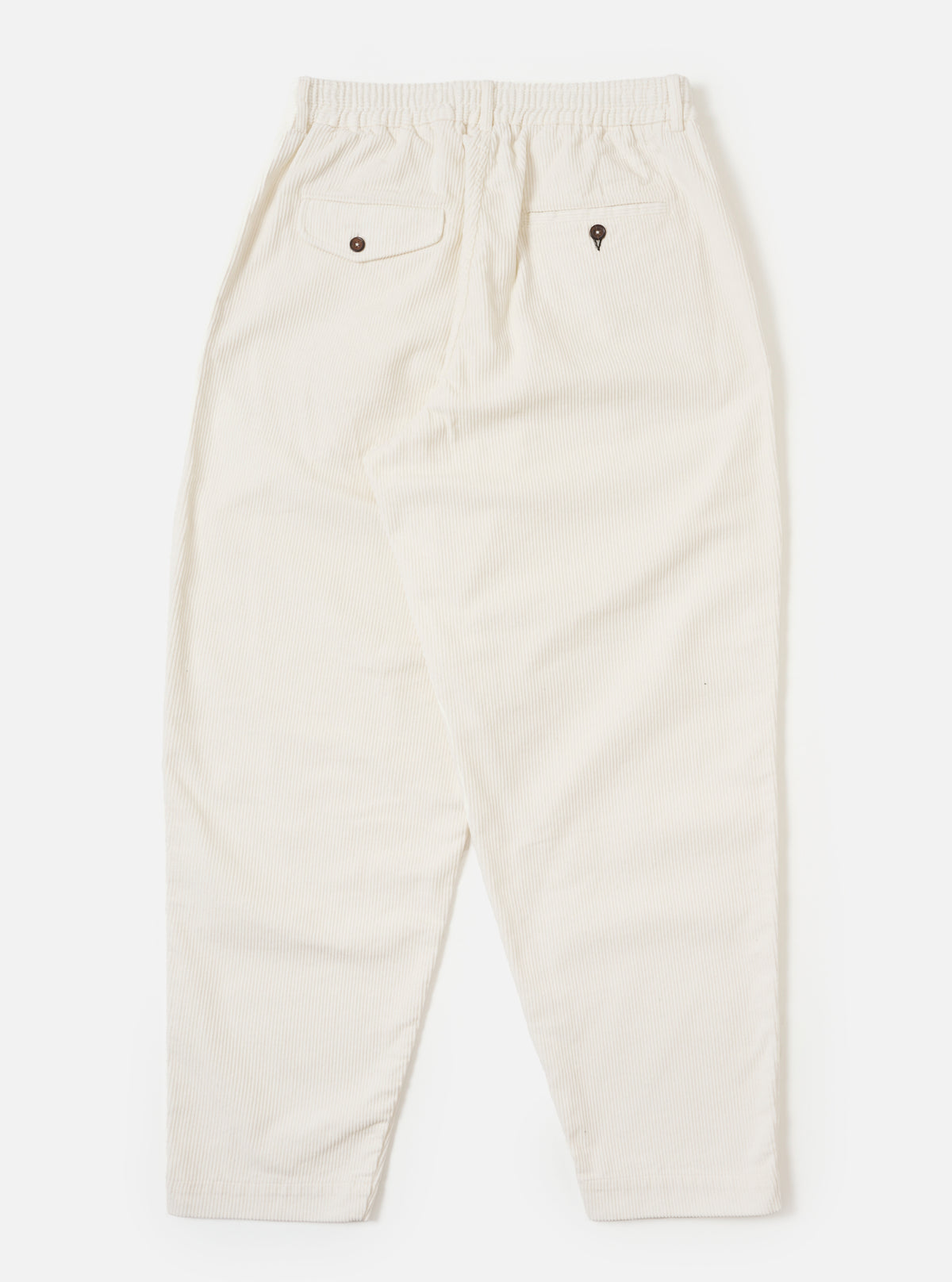 The back of ecru cord pleated track pant on a white background. The corduroy material is visible, as are the two back pockets with button closures.