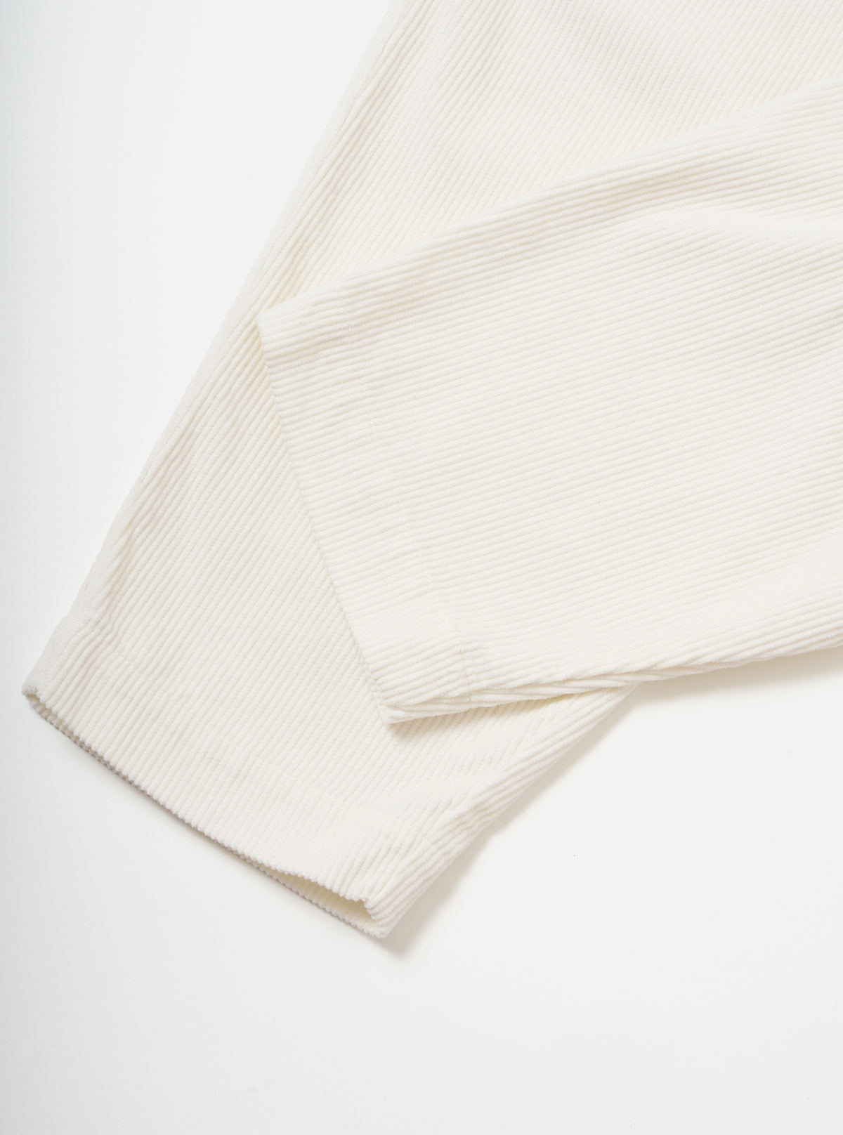 Close-up of the Ecru Cord Pleated Track Pant on a white background. The soft, textured corduroy material is visible, showcasing the pleated design and relaxed fit.