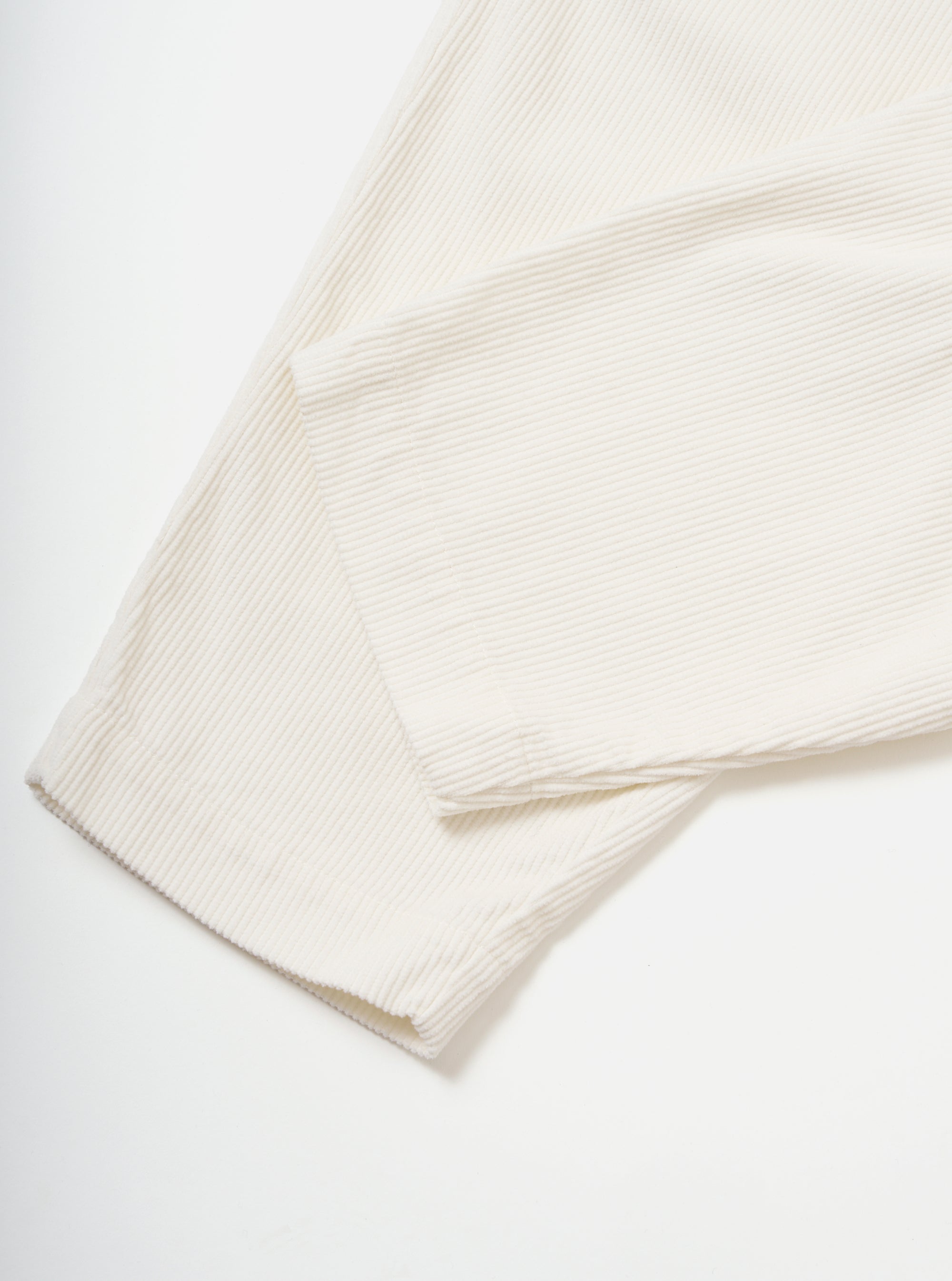Close-up of the Ecru Cord Pleated Track Pant on a white background. The soft, textured corduroy material is visible, showcasing the pleated design and relaxed fit.