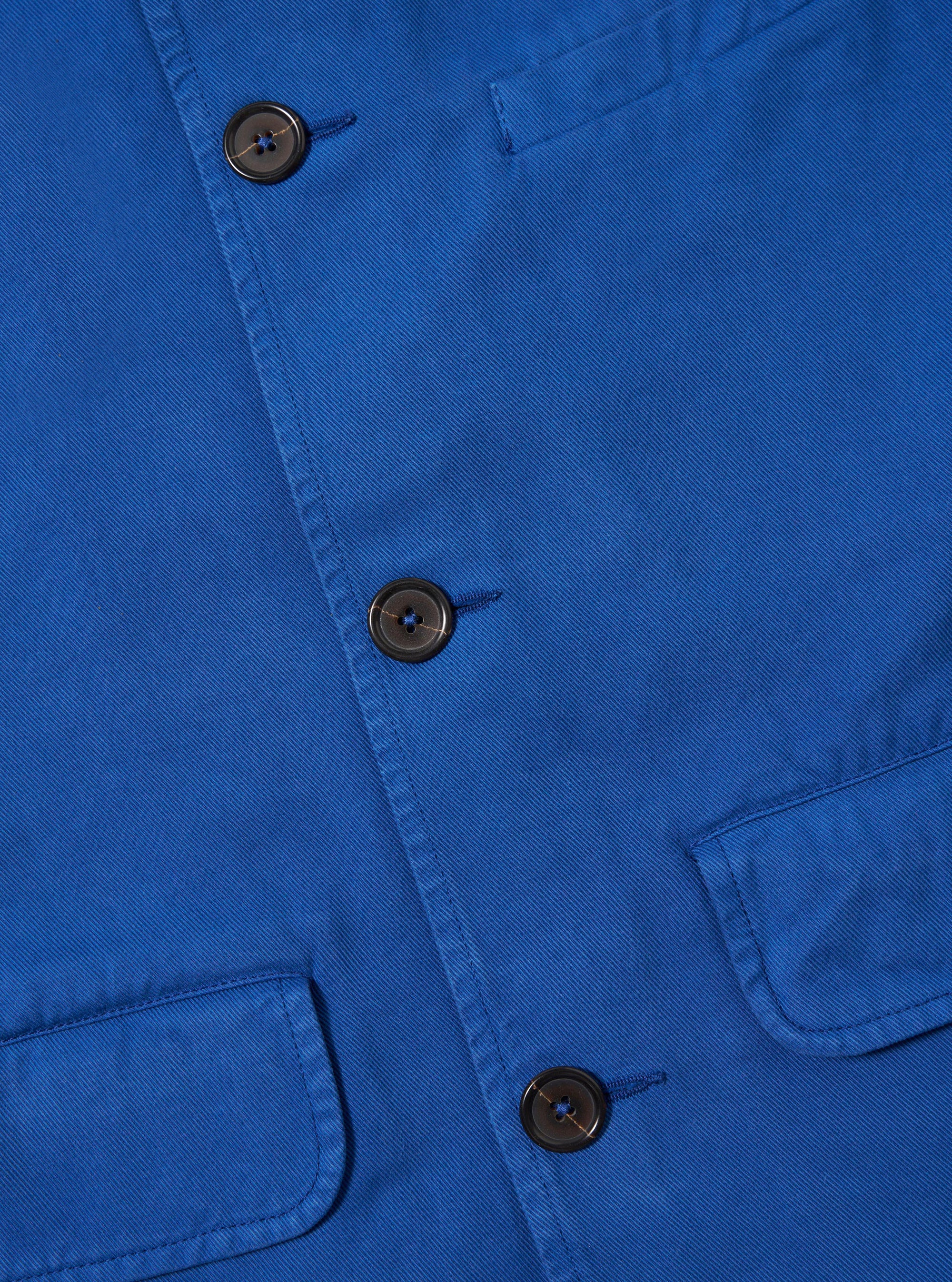 Close-up of the navy Derek Twill Warmus Jacket, showcasing the twill texture, buttons, and pocket detail. The jacket is neatly laid out on a flat surface.