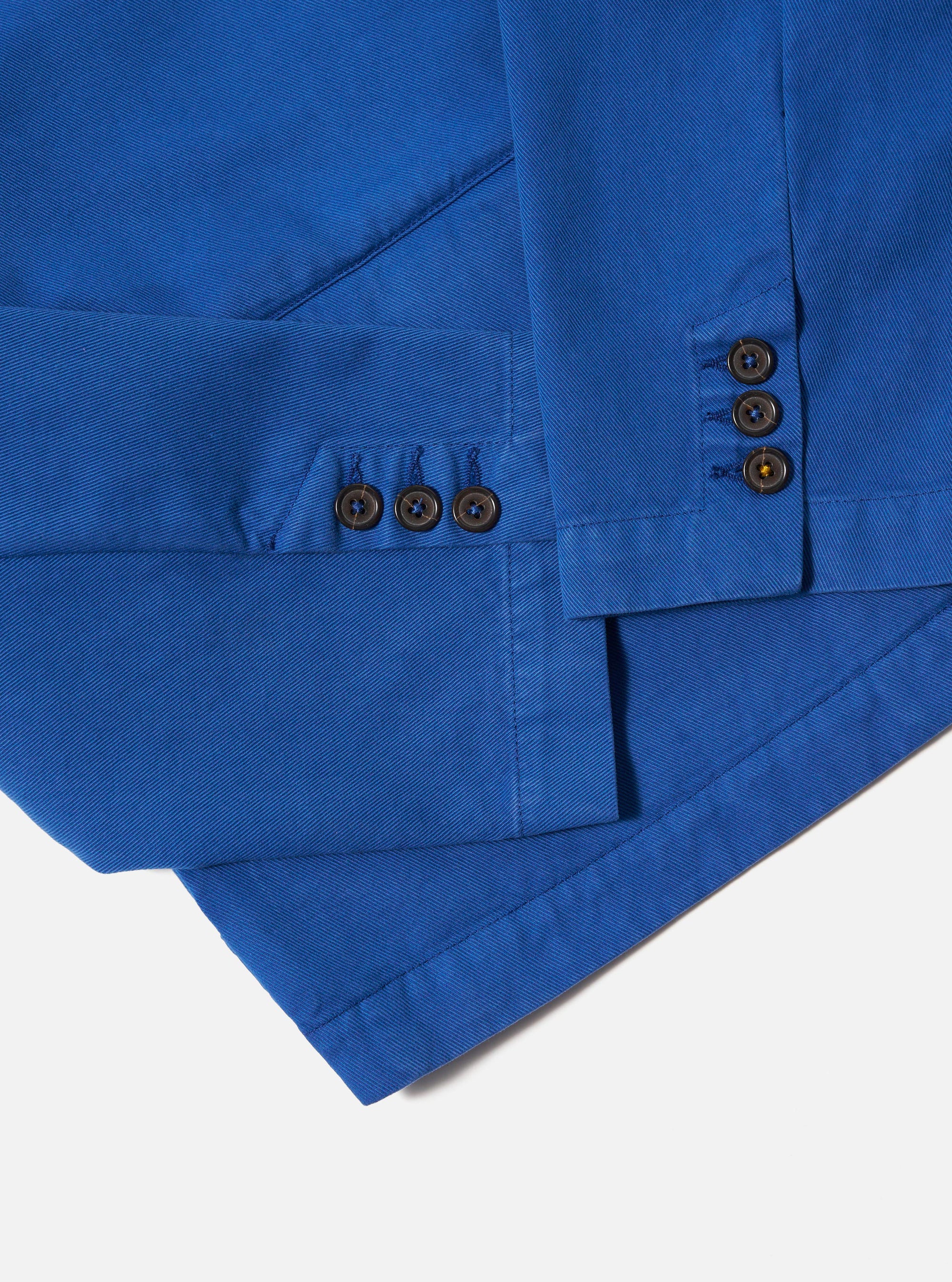 Close-up of the navy Derek Twill Warmus Jacket on a white surface. Shows the jacket's twill texture, sleeve buttons, and tailored fit.