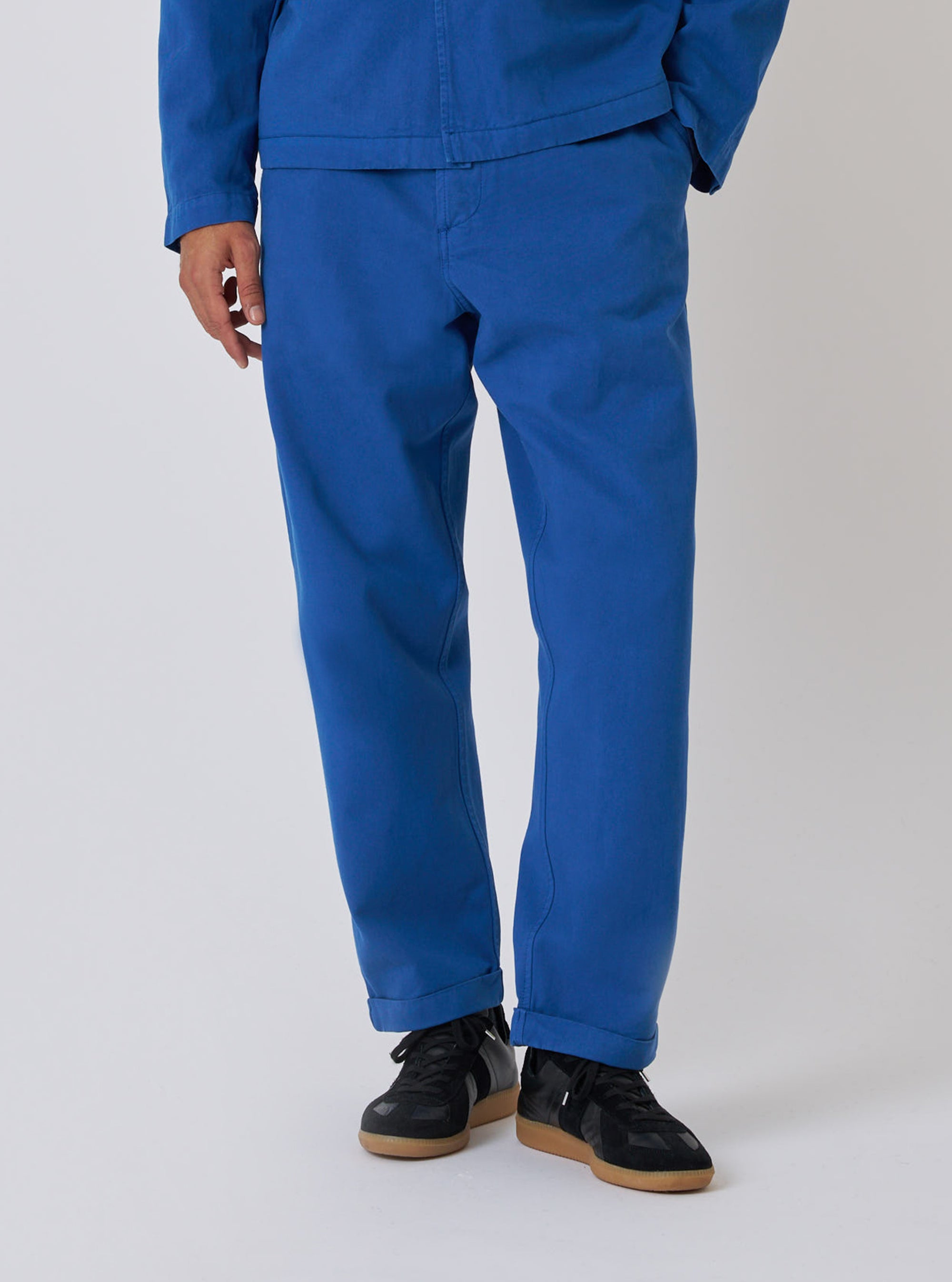 Model wears Navy Derek Twill Super Chino, a relaxed fit, in a studio shot on a white background. The twill material is a vibrant blue, paired with black sneakers.
