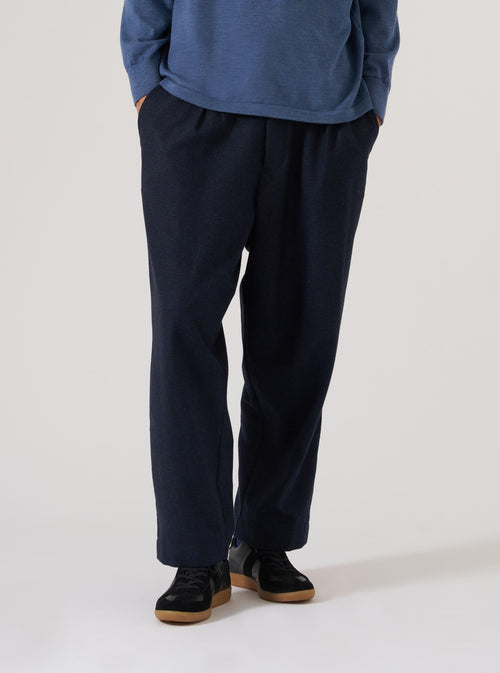 Studio shot of a model wearing the Navy Brushed Bari Oxford Pant. The pants are a relaxed fit. The background is a plain white.