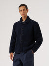 A man poses in front of a white background wearing the Navy Alvar Fleece Lancaster Jacket. The jacket is a dark navy fleece with a button-up front.
