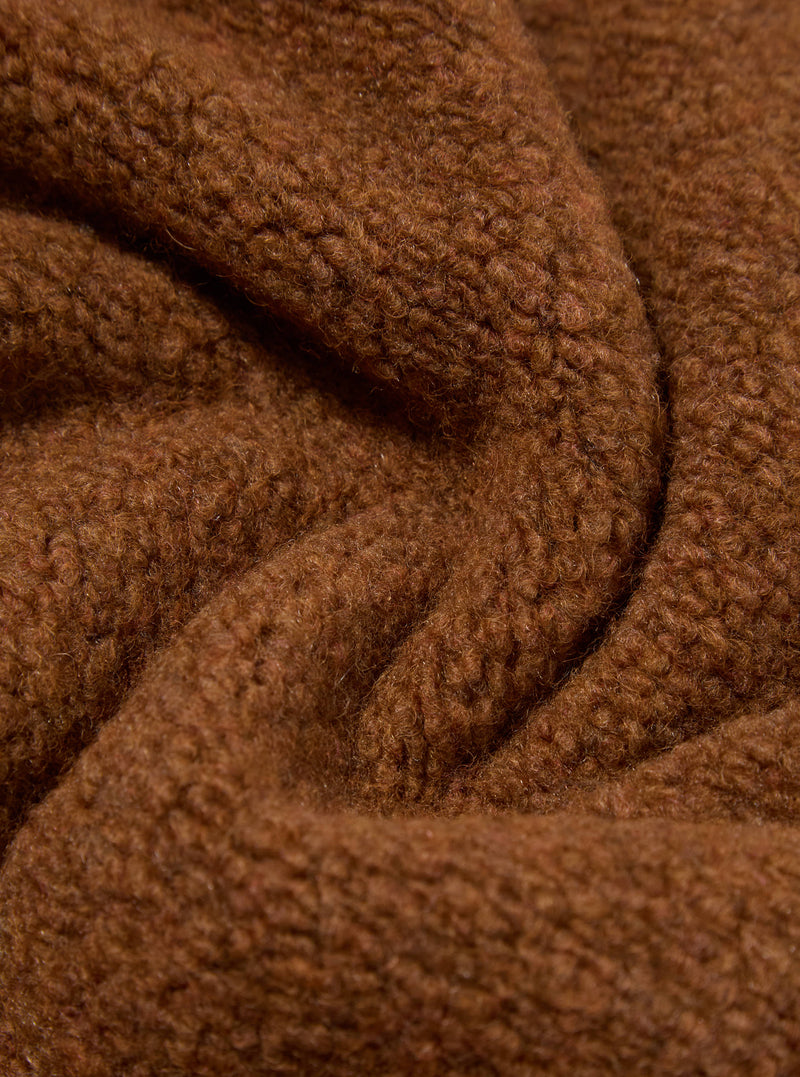 Close-up of the Cumin Alvar Fleece Travel Hoodie, showcasing the soft, brown fleece material in a studio setting. The fabric is draped to highlight its texture.