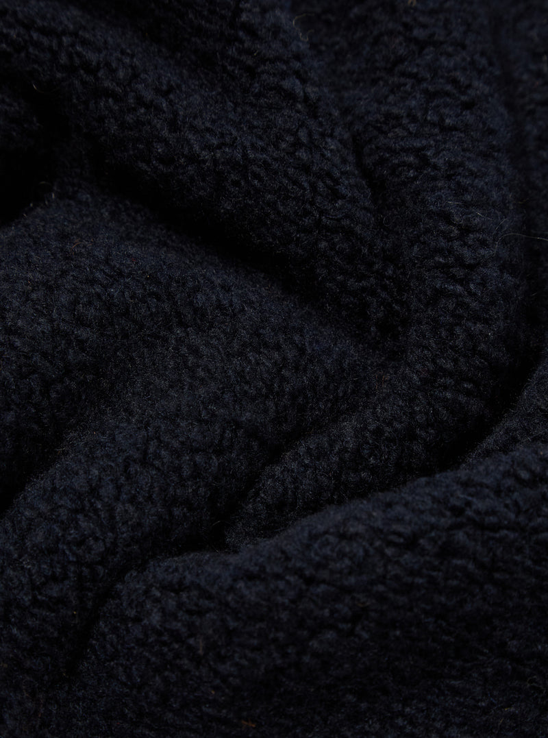 Close-up of the Navy Alvar Fleece Travel Hoodie, showing the soft, textured fleece material in a deep navy color. The fabric is draped to highlight its cozy feel.