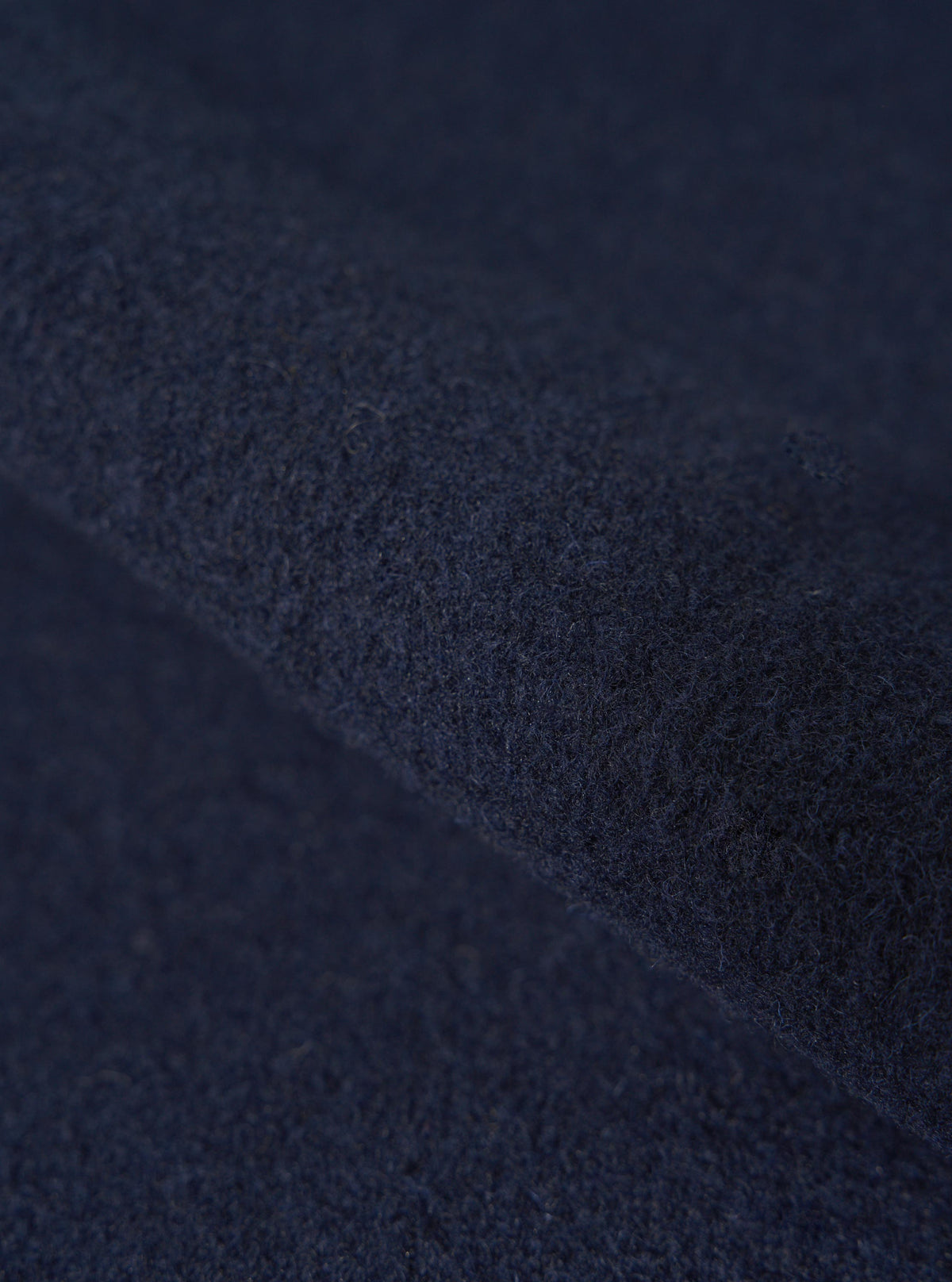 Close-up of the Navy Techno Melton Plain Zip Liner Jacket fabric. The rich navy material is folded, showcasing its texture and depth.