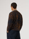 A man stands in front of a white background, wearing a Dark Navy/Brown Night Leopard Cardigan and dark pants. The cardigan features a unique leopard print design.