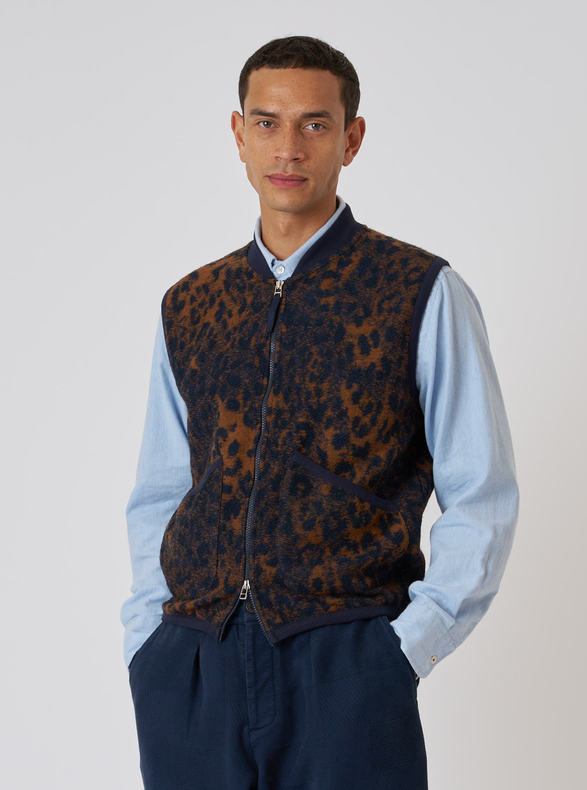 A model poses in a Dark Navy/Brown Night Leopard Zip Waistcoat against a white backdrop. The waistcoat features a unique leopard print and a zip-up design.