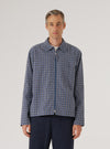 A man stands in front of a white background, wearing a Navy Oscar Cotton Zip Shirt with a geometric pattern and navy pants. The shirt is fully zipped.
