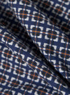 Close-up of the Navy Oscar Cotton Zip Shirt fabric. The shirt features a navy blue base with a white and orange geometric pattern. The cotton fabric is soft and textured.