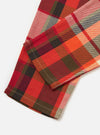 Close-up of the Red Earth Check Long Pyjama Set fabric. The red, orange, and brown plaid material is on a white surface, showcasing the soft texture and classic pattern.