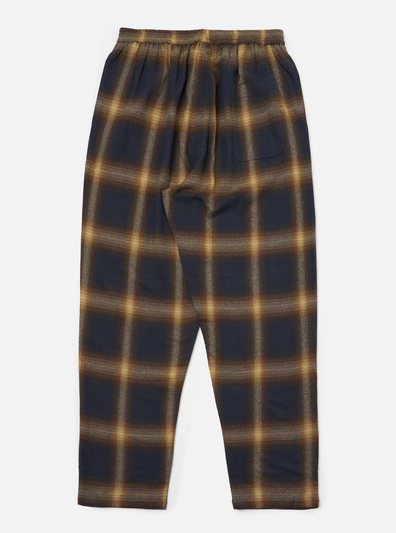 The Navy Canyon Check Pyjama Pant, laid flat on a white surface. The pants are a navy and tan plaid, with an elastic waistband.